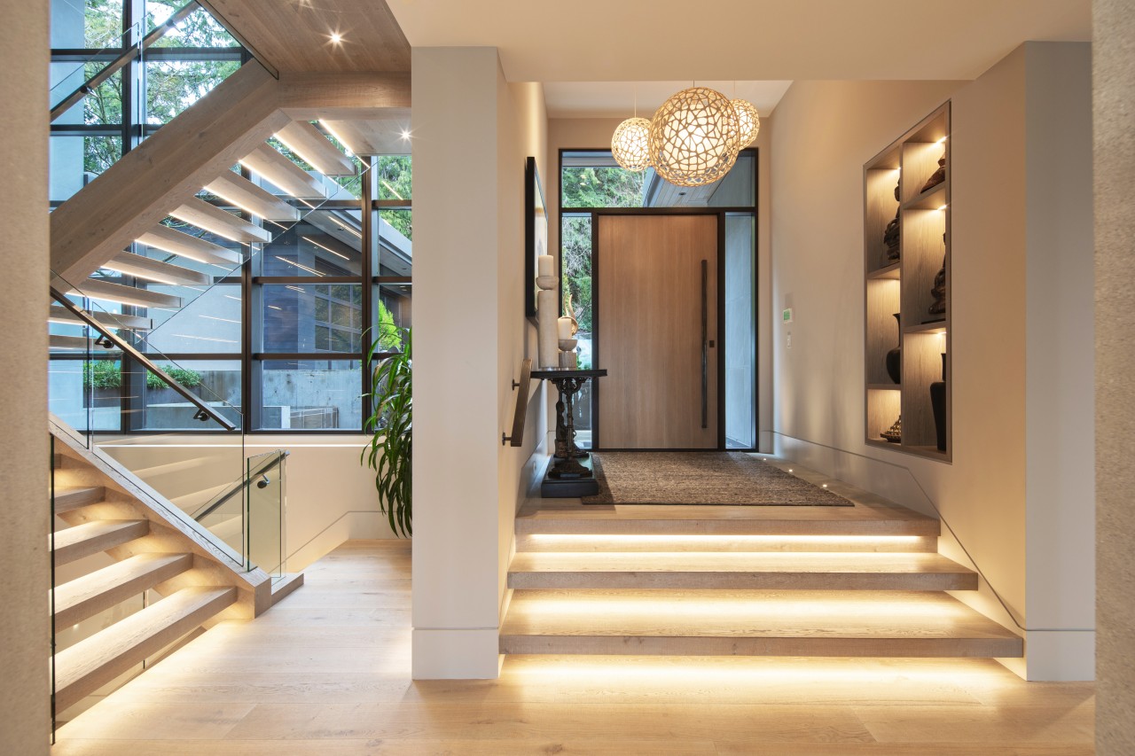Modern foyer with architectural staircase and LED step lighting in a luxury smart home in Metro Vancouver, designed and integrated by Graytek.